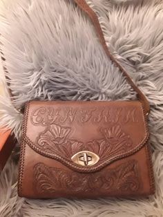 "Brand new purse for the Cynthia in your life.  Beautifully tooled,structurally sound this bag has 1 zip pocket and one pouch.  Two straps one small for security?  And the over the shoulder 34.5\"   Purse 10.5\" wide by 7.5\" tall & 4\" wide at bottom tapered to 2.5 @ top.  Interesting purple on brown print on inside leather." Western Purses, Western Life, Western Style Outfits, Unique Purses, Fashion Illustration Dresses, Hand Tooled Leather, Pretty Bags, Beautiful Sweater, Cute Bags