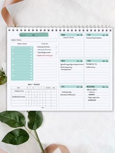 the printable planner is sitting on top of a table next to a plant and ribbon