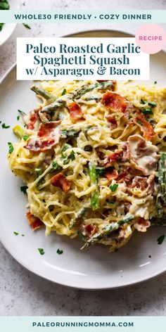 a white plate topped with pasta covered in bacon and spinach next to a glass of wine