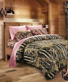 a bed in a room with wood paneling and pink comforter covers on it