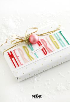 a gift wrapped in white paper with a red ornament on it