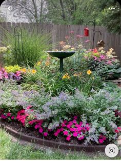 a bird bath surrounded by colorful flowers in a garden