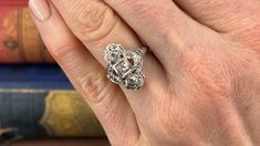 This fabulous Art Deco circa 1920s dinner ring features a pierced design with milgrain edging and etched floral designs. The ring is accented with nine (9) bead set old European cut diamonds. The ring measures 18.6mm at the top, rises 5.9mm above the finger, and tapers to 1.1mm wide by 0.7mm thick at the base of the shank. It is currently a size 5.5. Two of the diamonds have very minor chipping that cannot be seen without jewelers magnification. Art Deco Jewelry With Rose Cut Round Diamonds, Art Deco Rose Cut Round Diamond Jewelry, Art Deco Jewelry With Round Diamond Cut, Art Deco Hallmarked Jewelry For Wedding, Art Deco Hallmarked Wedding Jewelry, Art Deco Diamond Ring With Diamond Cut, Art Deco Diamond Rings For Collectors, Art Deco Diamond Accented Jewelry For Wedding, Art Deco Rose Cut Diamond Jewelry For Formal Events