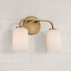 two light bathroom fixture with white glass shades on the wall and brick tiles behind it