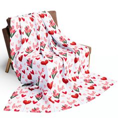 a white blanket with red hearts on it and a wooden chair in the foreground