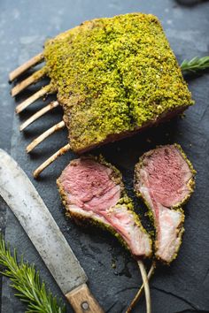 a piece of meat on a cutting board next to a knife and some rosemary sprigs