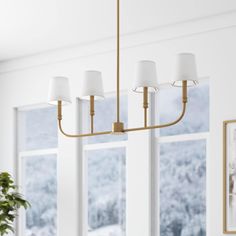 a chandelier hanging from the ceiling in a dining room with windows and potted plant