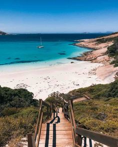 stairs leading down to the beach with boats in the water and sand on either side