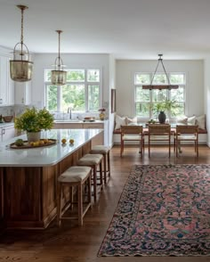 a large rug in the middle of a kitchen with wooden floors and white walls, along with an area rug on the floor