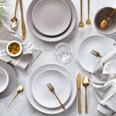 the table is set with white dishes and gold cutlery, along with silverware