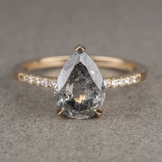 an engagement ring with a pear shaped diamond and pave diamonds on the band, set in yellow gold