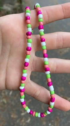 a hand holding a multicolored beaded necklace on it's thumbnail