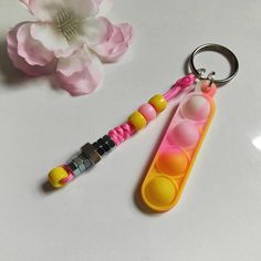 a pink and yellow keychain sitting on top of a table next to a flower