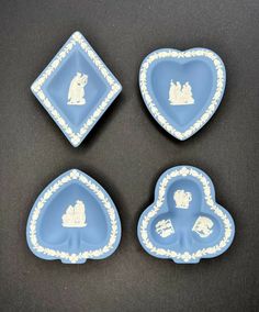 four pieces of blue and white porcelain with silhouettes on the plates in the shape of hearts