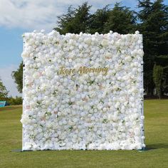 a large white flower covered wall in the middle of a field