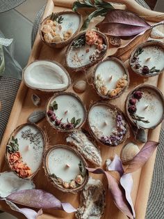 many candles are sitting in small bowls on a tray with leaves and other things around them