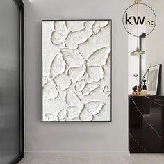 a white painting hanging on the wall next to a black and white cabinet in a room