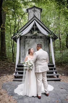 a bride and groom standing in front of a gazebo