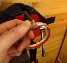 a hand holding a wrench in front of a piece of metal on a workbench