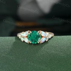 a ring with an emerald and opal stone in the center on a green surface