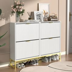 a white cabinet with shoes on top and flowers in vases next to the door