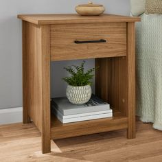 a small wooden table with a plant on top and books underneath it next to a bed