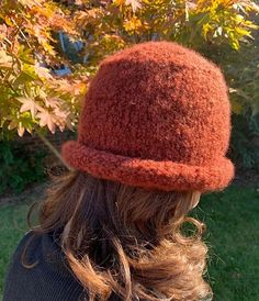 a woman wearing a red hat standing in front of a tree with leaves on it