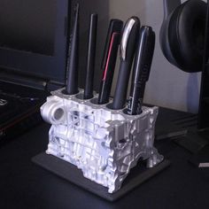 a pen holder made out of an old computer keyboard and other electronic gadgets sits on a desk next to a laptop