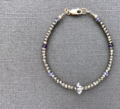 "Herkimer Diamond Bracelet Earthy and elemental, pyrite is a terrific canvas for gemstones. These faceted beads positively glimmer in bronze and gold, providing a metallic sparkle that is quite striking. Highlighted at the front of this piece is a natural, Herkimer crystal, often known as a Herkimer diamond due to its clarity. Tanzanite and amethyst gemstones add subtle sparks of violet. Bracelet shown measures 7\" (18cm). Fashioned on professional beading wire which provides strength and lovely Silver Gemstone Bead Rondelle Bracelets, Silver Rondelle Bracelets With Gemstone Beads, Silver Amethyst Beaded Bracelets With Faceted Beads, Silver Rondelle Crystal Bracelet With Gemstone Beads, Silver Crystal Bracelet With Gemstone Beads, Healing Silver Beaded Bracelets With Faceted Beads, Silver Amethyst Beaded Bracelet With Faceted Beads, Silver Beaded Bracelets For Healing, Silver Crystal Bracelet With Rondelle Gemstone Beads