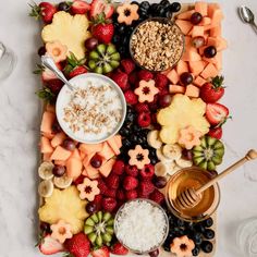 a platter filled with fruit, cereals and other foods on top of a table