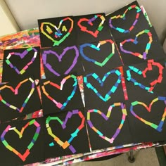 several pieces of art made to look like hearts on black paper with colored crayons