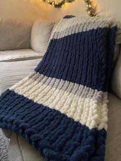 a blue and white blanket sitting on top of a couch next to a christmas tree