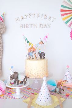 there is a birthday cake and party hats on the table in front of the wall