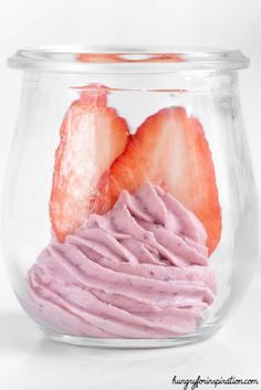 two strawberries in a glass jar with pink frosting on the top and bottom