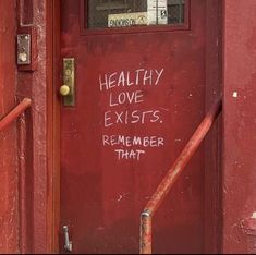 a red door with writing on it that says, healthy love exists remember that