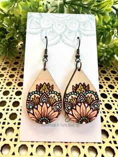 a pair of wooden earrings with floral designs on them sitting on top of a card