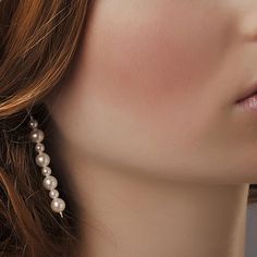 a close up shot of a woman's face wearing pearled earrings