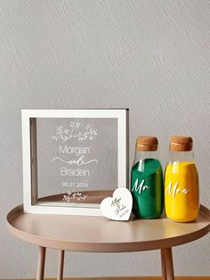 two jars are sitting on a table next to a framed photo and a personalized name tag