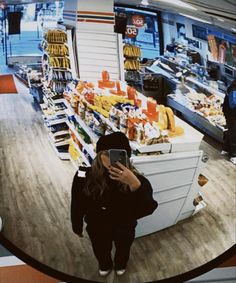 a woman is looking at her cell phone in a grocery store's selfie