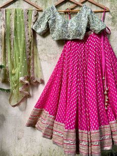 A three-piece fuchsia and olive green zari lehenga set from the Priti Sahni collection. This gorgeous georgette fuchsia butti lehenga with a heavy zari border of sequin work is paired with a raw silk olive green mirror blouse in pearl, and zardozi hand embroidery. The lehenga has side hanging ball tassels to the waistline. And the blouse has pearl tassel tie-up at the back. This outfit is completed with an olive green sequin work net dupatta with scalloped edging. Best Lehenga Designs, Zari Lehenga, Off Shoulder Lehenga, Lehenga Designs Latest, Mirror Blouse, Bridal Lehenga Designs, Long Frock Designs, Latest Bridal Lehenga, Raw Silk Lehenga