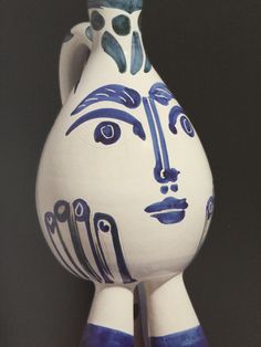 a blue and white vase with a face painted on it's side, against a black background