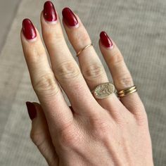 a woman's hand with red nail polish and gold ring