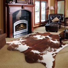 a living room filled with furniture and a cowhide rug on the floor in front of a fire place