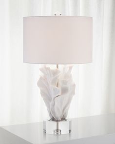 a lamp that is sitting on top of a table in front of a white curtain