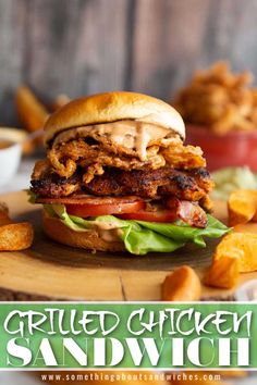 a grilled chicken sandwich with lettuce and tomato on a wooden cutting board