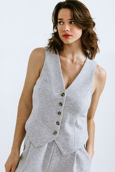 A ponti knit vest featuring V neckline, sleeveless and button down. Matching Bottom FP1013Details:Self : 55% Cotton 40% Polyester 5% SpandexSize & Fit- Model is 5`8" And Wearing Size Small- Measurements Taken From Size Small- Approx. Length: 21"e Gray V-neck Vest For Workwear, Gray Fitted V-neck Sweater Vest, Fitted Sleeveless Gray Sweater Vest, Gray Sleeveless Vest For Layering, Sleeveless Gray Vest For Layering, Fitted Gray Vest For Layering, Gray V-neck Vest For Work, Gray Sleeveless Sweater Vest For Work, Womens Gray Vest