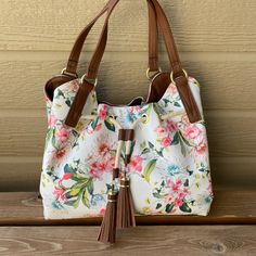 So Cute For Spring! Come In Style With This Bag That Pairs Well With A Summer Dress Or Dresses Up A Pair Of Jeans! This Super Cute Floral Purse Satchel Style Has The Following Features: Features: Super Cute Tassels And A Brown Double Handle Closure Type: Zipper In Middle Area, Snap For Entire Top Pockets: 2 Inside Slip Pockets, 1 Inside Zip Pocket Metal Color: Gold Tone Approx. Measurements: 8 Depth/Inches, 11 Height/Inches, 14 Width/Inches Handle Drop Length: Approx. 9 Inches Base Material: 100 Casual White Bag With Floral Print, Casual White Floral Print Bag, Everyday White Shoulder Bag With Floral Print, White Floral Print Shoulder Bag For Everyday Use, White Shoulder Bag For Day Out, Everyday White Floral Print Shoulder Bag, White Floral Print Shoulder Bag, White Floral Print Tote Shoulder Bag, Floral Purse