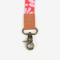 an orange and pink flowered keychain with a metal hook on the end