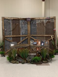 an outdoor display with plants and pictures on the wall, in front of a white tiled floor