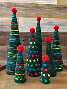 crocheted christmas trees with pom - poms on them are sitting on a table